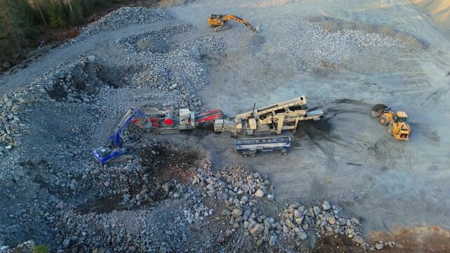 Espoo, Finland-April 14, 2025: Heavy machinery operating in a stone crushing plant, processing rocks and producing crushed stone in a building lot surrounded by forest in Finland during springtime