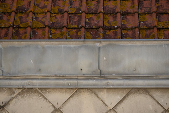 Weathered roof tiles with moss and zinc flashing detail