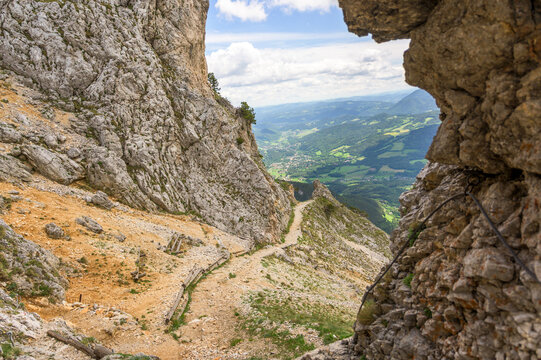 A scenic view of the Rax mountain trail in Austria showcases a winding path leading through rugged rock formations and earthy tones of brown and gray rocks contrasted with lush greenery