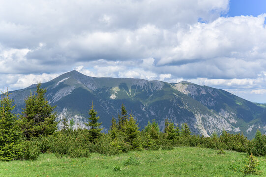 The stunning Rax Mountains display rugged peaks beneath a blue sky dotted with fluffy clouds
