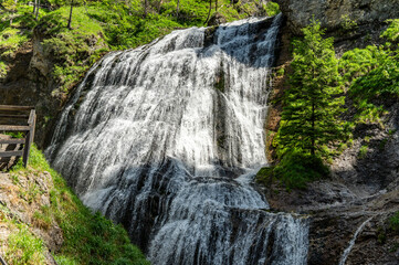 A stunning waterfall cascades down lush green cliffs in Wasserlochklamm Austria surrounded by vibrant foliage © nordantin