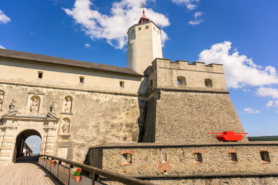 Forchtenstein, Austria - June 6, 2022: The castle features a prominent stone tower under a clear blue sky with bright clouds illuminating the historic structures and scenic bridge
