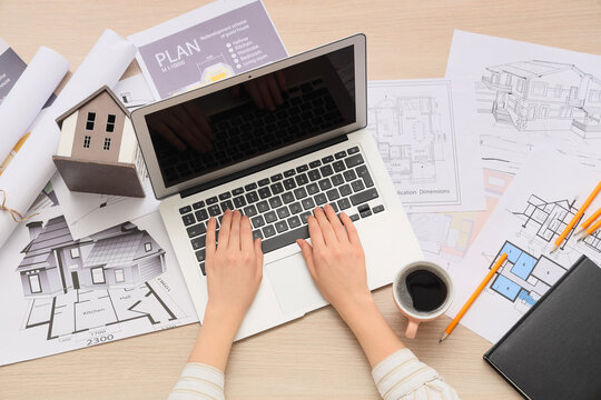 Architect working on laptop with house model and blueprints, real estate and construction planning