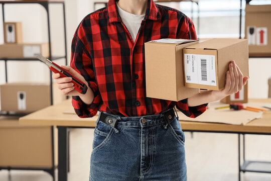 Person in plaid shirt holding a box cutter and a cardboard package for shipping and delivery service