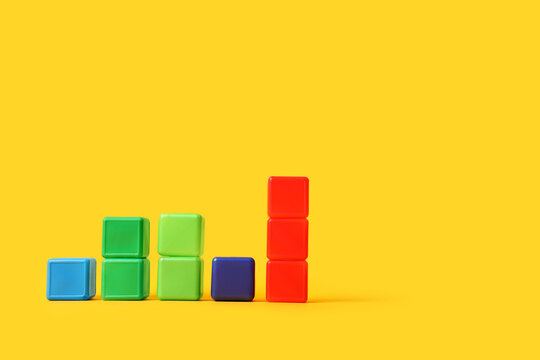 Colorful plastic toy blocks arranged as a bar graph on a bright yellow background data visualization and growth, this arrangement data visualization growth and progress in various fields