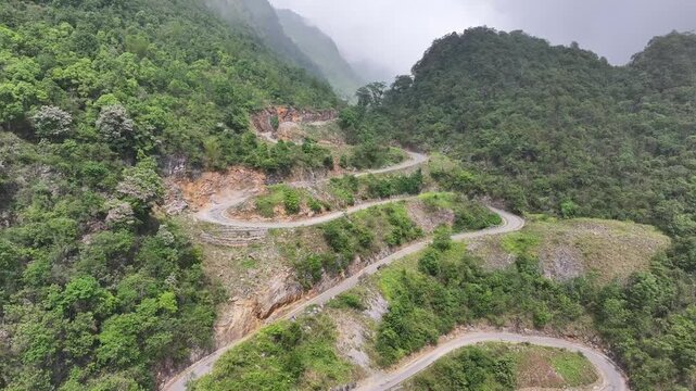 Aerial drone footage of the stunning Khau Coc Cha pass, a steep zigzagging mountain road in Bao Lac District, Northern Vietnam, surrounded by lush green karst peaks.