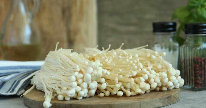 Woman taking raw enoki mushrooms from table, closeup
