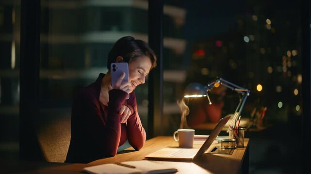 Smiling businesswoman phone call evening office. Happy lady working laptop night