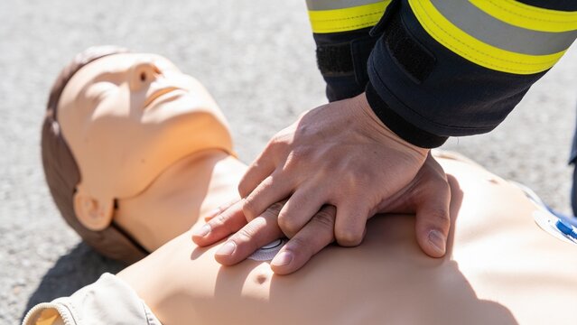 A close-up view of a person performing CPR compressions on a medical training mannequin dummy.