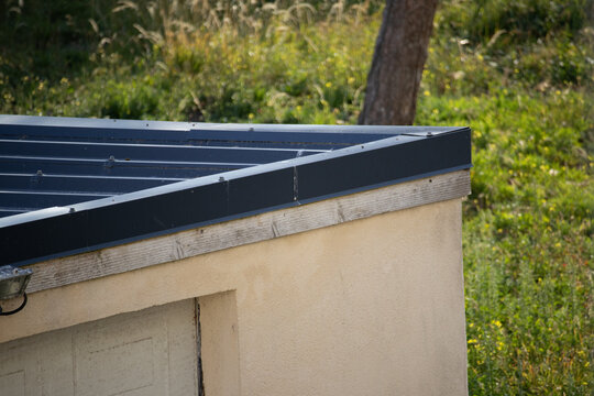 Modern flat roof edge with metal flashing on small building