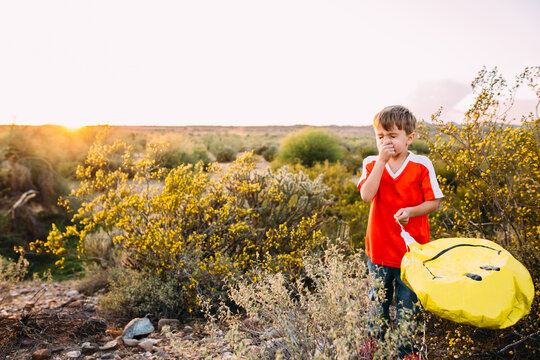 boy in desert holding balloon about to sneeze