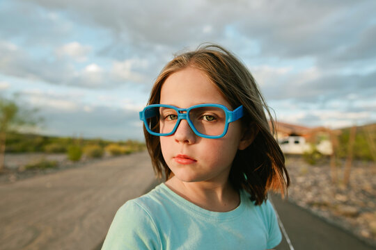 girl in glasses standing in desert landscape 