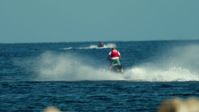Man on a jet ski speeding across the open ocean, creating white water spray, enjoying summer water sports