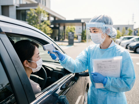 病院の駐車場でドライブスルーの検温検査に応じる発熱外来の女性