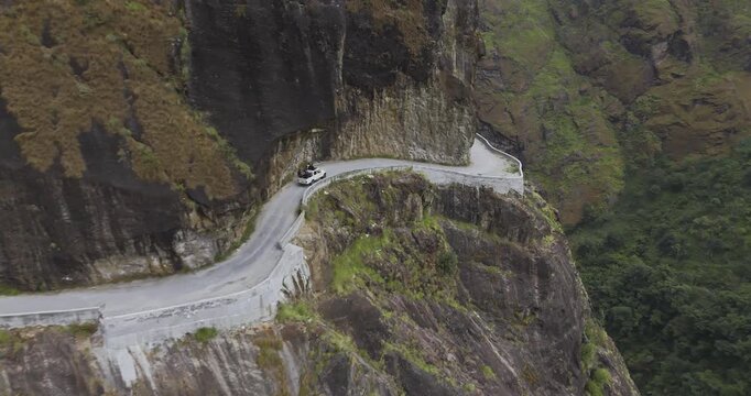 Annapurna region Nepal, drone gliding shot tracking an off road jeep as it moves along a narrow, dangerous dirt road carved into a steep mountain cliff face above the Marsyangdi River gorge.