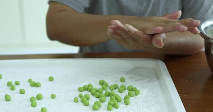 Hands carefully molding traditional bua loi dough. highlighting the artisanal and handmade cooking technique to create the authentic thai bua loi dessert.