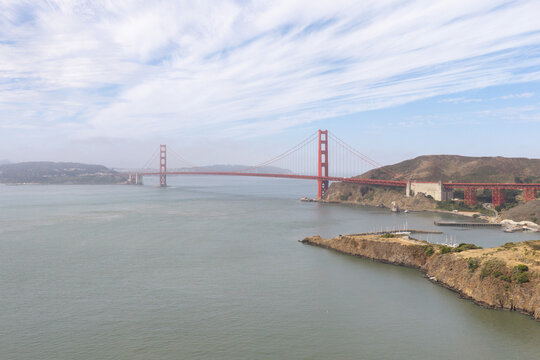 Golden Gate Bridge connects San Francisco to Marin County, offering an iconic landmark view with its distinctive orange-red towers, suspended over the waters of San Francisco Bay under a cloudy sky