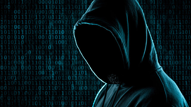 Shadowy Figure Behind Binary Code: A person in a hooded sweatshirt, their face obscured by shadow, stands against a backdrop of glowing blue binary code.