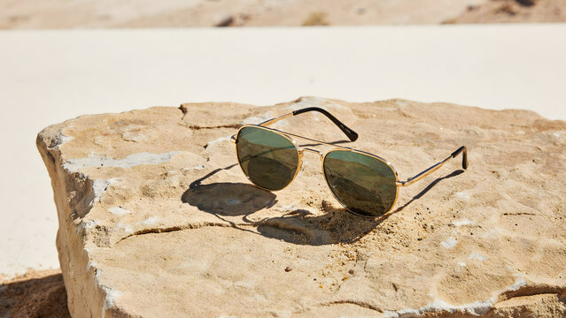Aviator sunglasses resting on a weathered sandstone rock in the desert