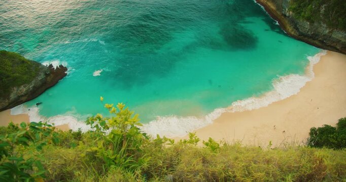 Scenic vista of turquoise bay with white sand beach surrounded by cliffs in Bali