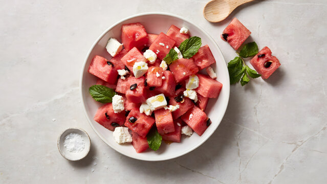 Fresh watermelon salad with crumbled feta cheese and mint leaves on gray table