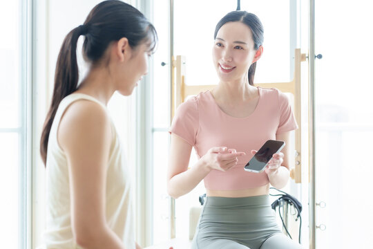 ピラティススタジオでスマートフォンを見せる女性