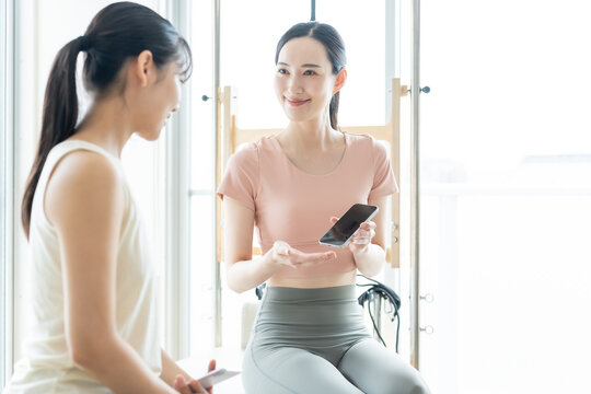 ピラティススタジオでスマートフォンを見せる女性