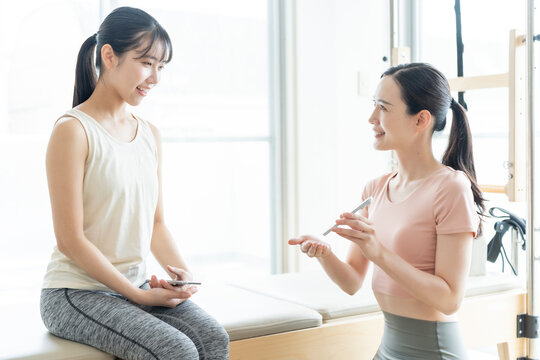 ピラティススタジオでスマートフォンを見せる女性