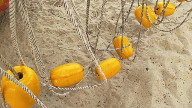 Yellow Beach Buoys on braided rope hanging above the Sand on the beach. Top view cinematic motion 