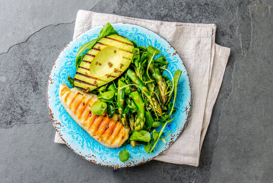 Green salad with grilled avicado and grilled chicken in blue plate