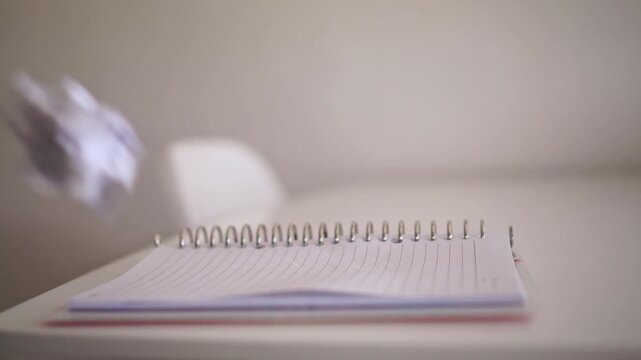 Crumpled paper balls are thrown in to a book on a desk. illustrating frustration, mistakes, and the creative process at work.