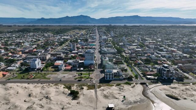 Arroio do Sal aerial pull back from beachfront street toward distant mountains
