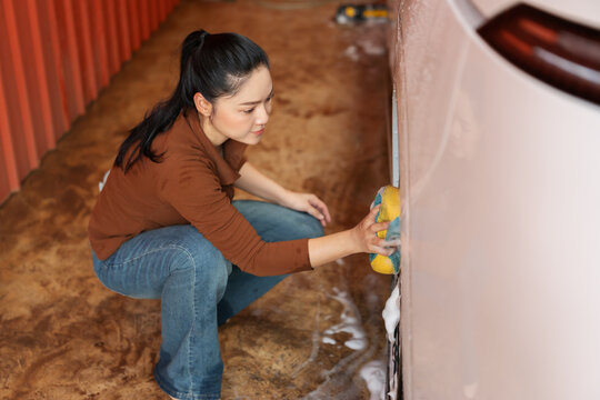 woman washing car wheel with sponge and foam in a self-service car wash station