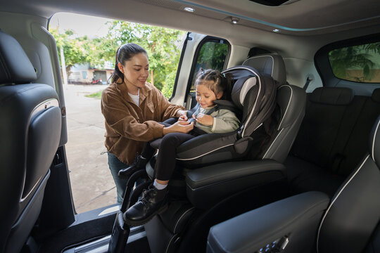 mother is fastening safety belt to preschool child girl in car seat, safety baby chair travelling
