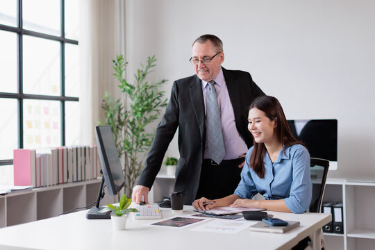 Diverse business team collaborating on project, experienced male manager mentoring young female intern, providing guidance and support in modern office workplace