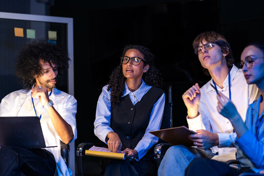 Candid moment as a diverse, multiethnic software team attend the team session together in a modern technology office bathed in blue light, showcasing a diverse, multiethnic team of young