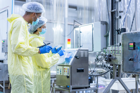 Technical team checking manufacturing machinery, Industrial quality assurance team monitoring production process, Quality control inspectors examining tin can on production line in food factory