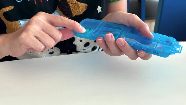 Static Close-Up of Hands Taking Medication from Blue Pill Box