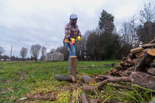 A lumberjack cutting logs in the countryside is getting ready for winter