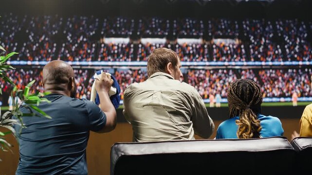 Soccer supporters on couch upset by goal, interactive match broadcast transporting them close to the stadium pitch, heightening their negative emotions for immersive home sports viewing.