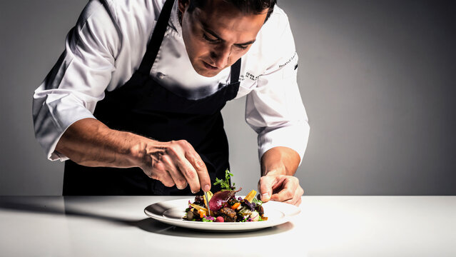 High-end chef plating gourmet fine dining dish in studio kitchen, artistic composition, dramatic soft lighting, detailed textures of food and plating, minimalistic background, luxury culinary concept.