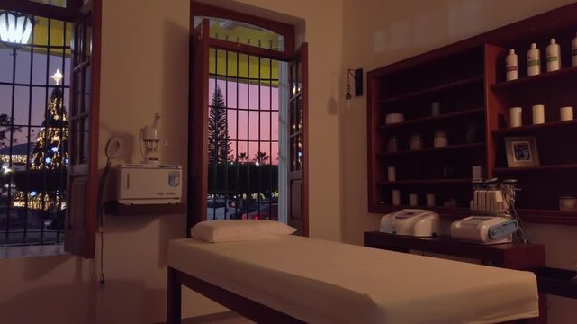 Smooth dolly in inside luxury spa treatment room with massage table at sunset