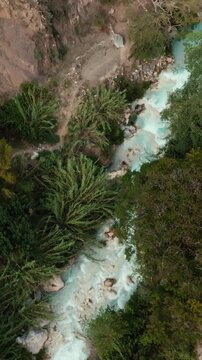Aerial view of the turquoise Tolantongo river flowing through a lush green canyon