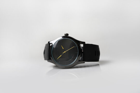 Minimalist Black Analog Watch with Gold Hands and Rubber Strap on White Background