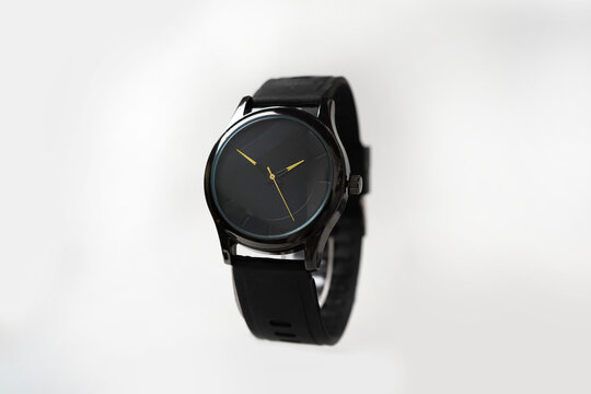 Minimalist Black Analog Watch with Gold Hands and Rubber Strap on White Background
