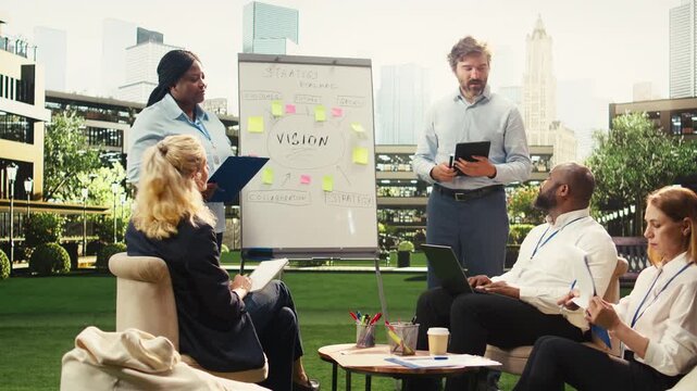 Diverse business people pointing to project timeline to build strategy on vision board during outdoor work session, leading coworkers through growth ideas on urban terrace, for business planning.