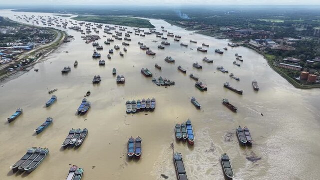 A broad drone view captures thousands of tons of cargo capacity sitting idle as lighter ships group together for safety on the Karnaphuli River in Chattogram, Bangladesh. 