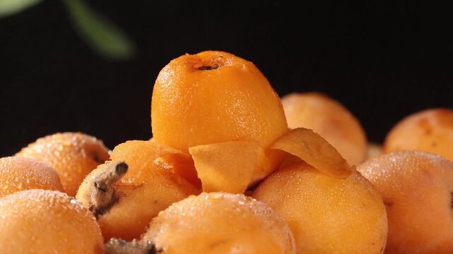 Close-up of fresh peeled loquat fruit with water droplets on a pile of loquats