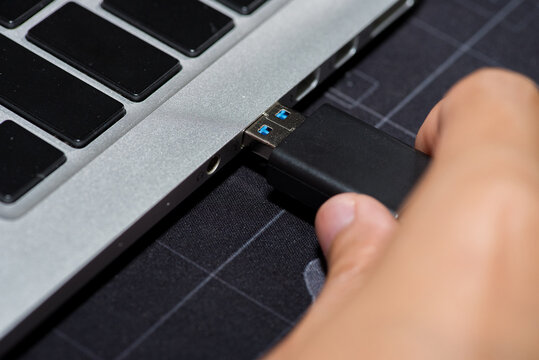 close-up image shows the use of a USB flash drive to connect to a laptop.
Hand inserting Flash drive memory drive plugged into a computer laptop port.