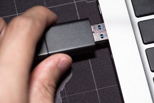 close-up image shows the use of a USB flash drive to connect to a laptop.
Hand inserting Flash drive memory drive plugged into a computer laptop port.
